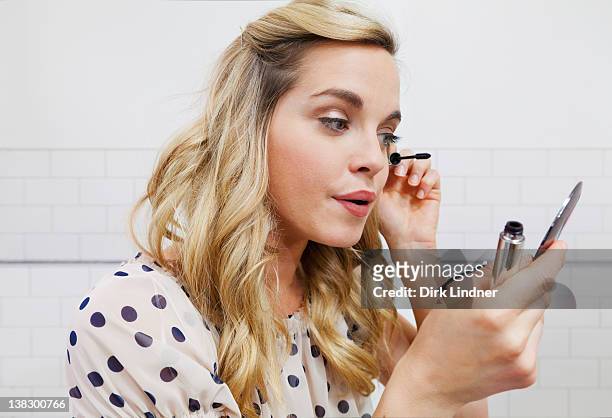 woman applying mascara in mirror - woman mascara stock pictures, royalty-free photos & images