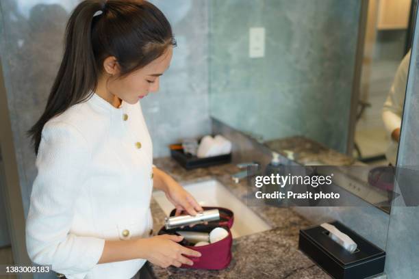 asian woman packing toiletries/cosmetics into a washbag to prepare the luggage for traveling on business trips abroad"r - beauty case stockfoto's en -beelden