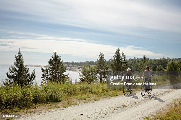 couple bicycling on rural dirt path - velo stockfoto's en -beelden