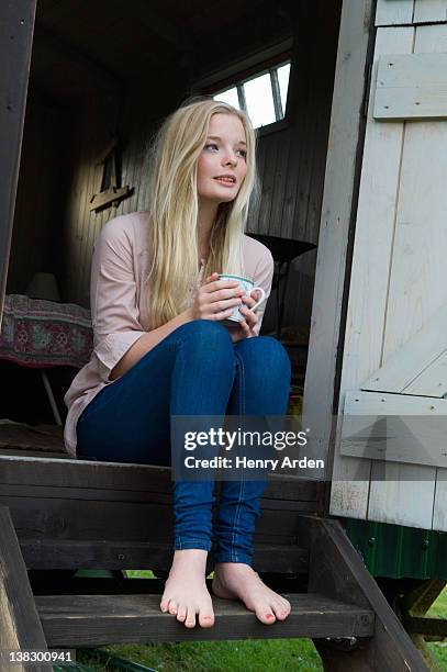 teenage girl having coffee on doorstep - teen girl barefoot at home stock pictures, royalty-free photos & images