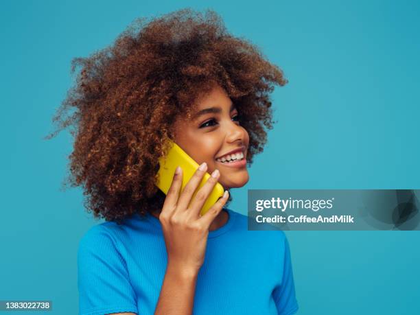 hermosa chica sonriente con peinado rizado usando un teléfono inteligente - chica joven fotografías e imágenes de stock