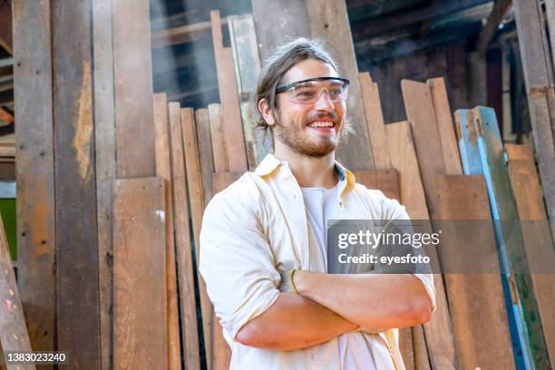 carpenter  is working in workshop. he is sawing a plank. - eye protection stock pictures, royalty-free photos & images