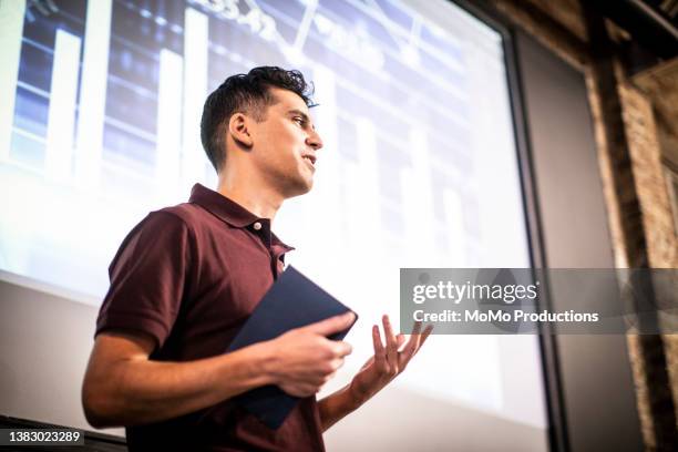 young professional man giving presentation in modern office space - präsentieren stock-fotos und bilder