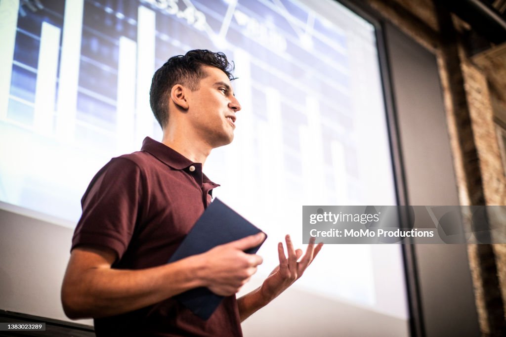 Young professional man giving presentation in modern office space