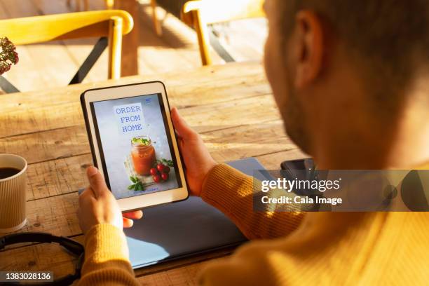male restaurant owner looking at delivery website on digital tablet - looking over shoulder stockfoto's en -beelden