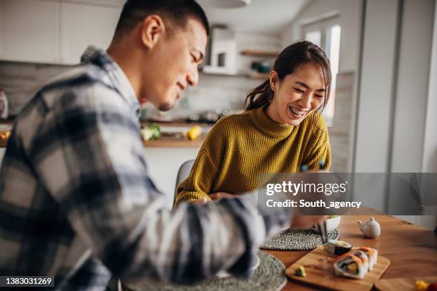 pareja comiendo sushi en casa - pareja de mediana edad fotografías e imágenes de stock