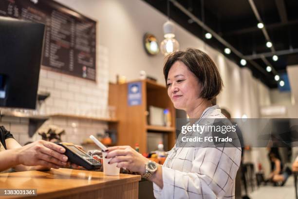 asian businesswoman paying with qr with mobile in a coffeeshop - bar code imagens e fotografias de stock