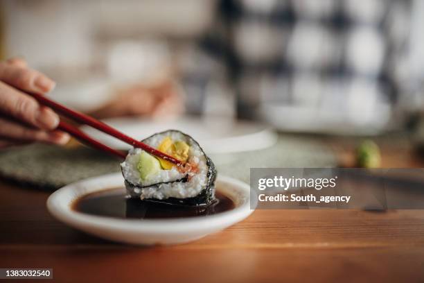 woman is dipping sushi in soy sauce - soy sauce stock pictures, royalty-free photos & images