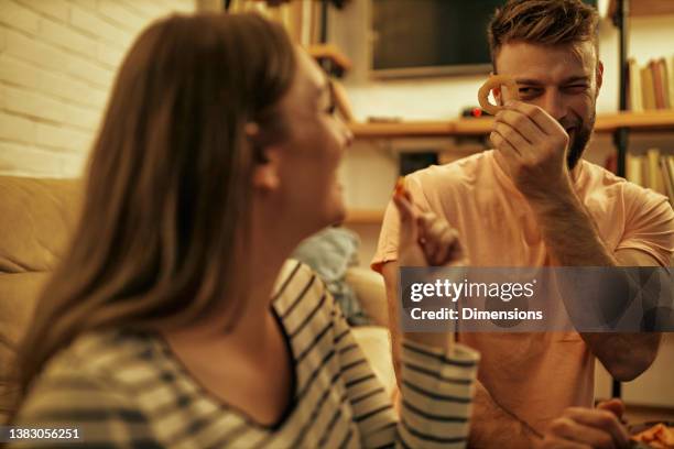cute couple bonding at home and eating fast food - onion ring stock pictures, royalty-free photos & images