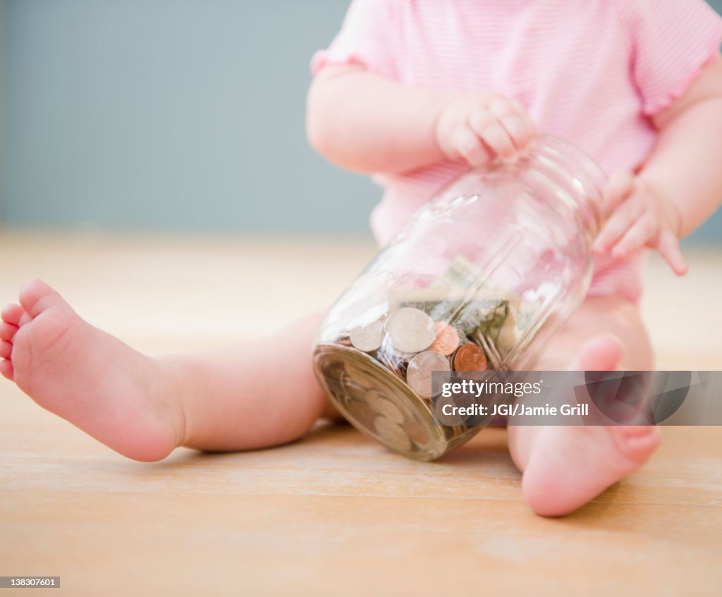 Caucasian baby playing with jar of coins