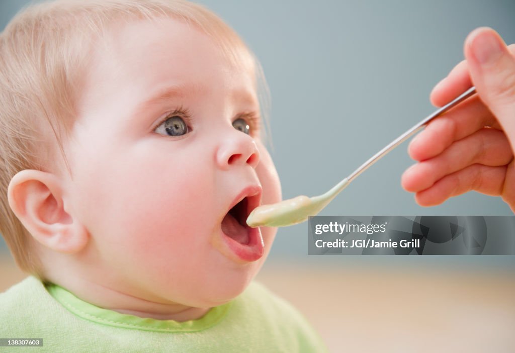 Mother feeding Caucasian baby