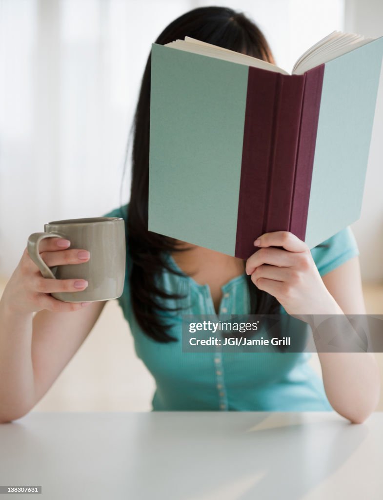 Korean woman drinking coffee and reading book