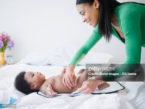 african american mother changing son's diaper - nappy change stock pictures, royalty-free photos & images