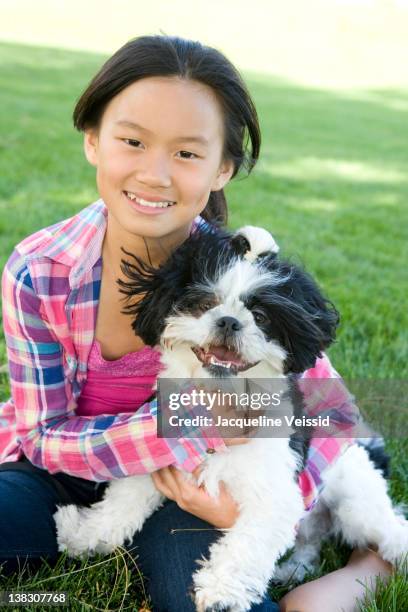 chinese girl sitting in grass with shih tzu dog - child holding toy dog stock pictures, royalty-free photos & images