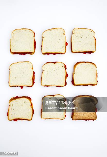 peanut butter and jelly sandwiches, one on whole wheat bread - peanut butter and jelly sandwich stock pictures, royalty-free photos & images
