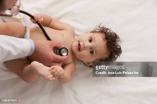 doctor examining mixed race baby girl - doctor and baby stock-fotos und bilder