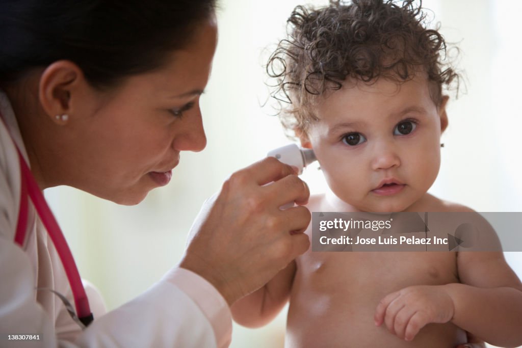 Doctor examining baby girl's ear