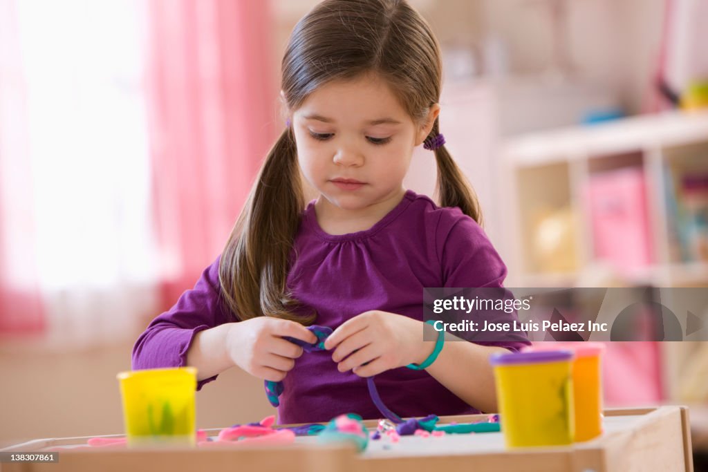 Mixed race girl playing with clay