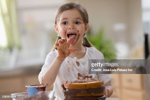 mixed race girl frosting cake and licking fingers - girls licking girls stock pictures, royalty-free photos & images