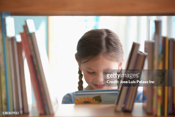 caucasian girl taking book from shelf - child reading stock pictures, royalty-free photos & images