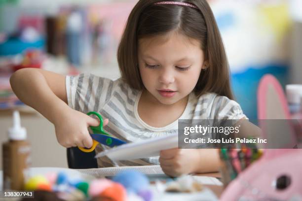 caucasian girl cutting paper with scissors - schere stock-fotos und bilder