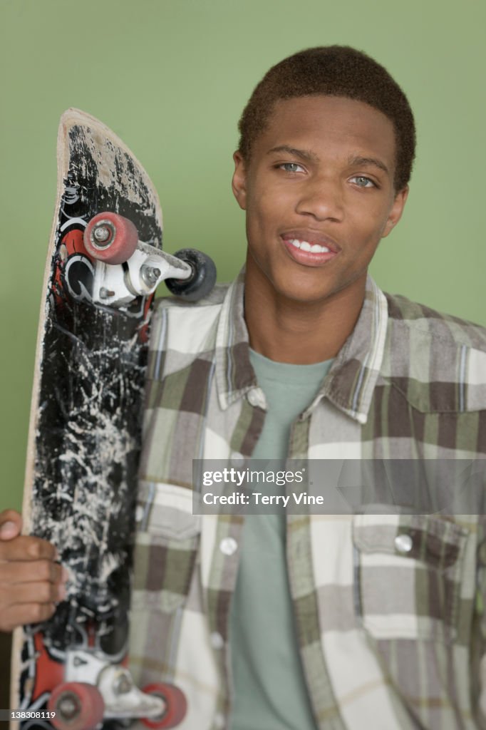 Mixed race teenager holding skateboard