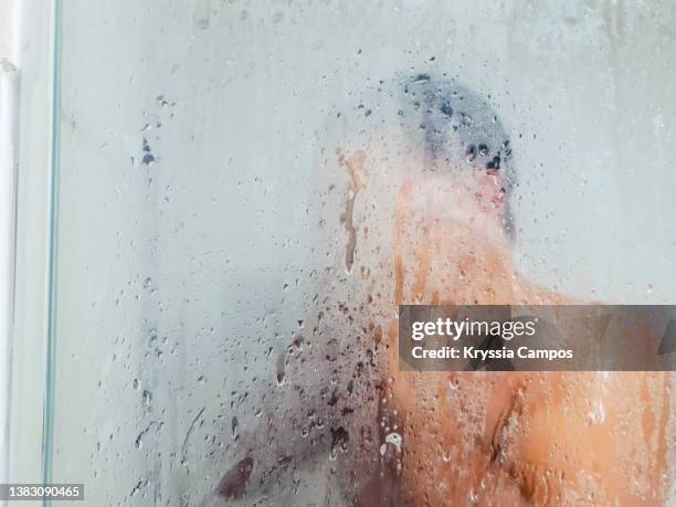 man in steamy bathroom taking a bath - hot shower stockfoto's en -beelden