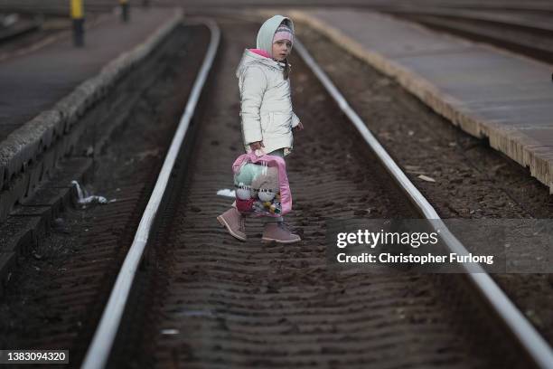 Young refugee girl fleeing Ukraine walks across the tracks as she arrives at the border train station of Zahony on March 08, 2022 in Zahony, Hungary....