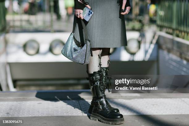 Guest poses wearing black leather boots and a Prada crystal embellished bag after the Miu Miu show at the Palais de Iena during Paris Fashion Week -...