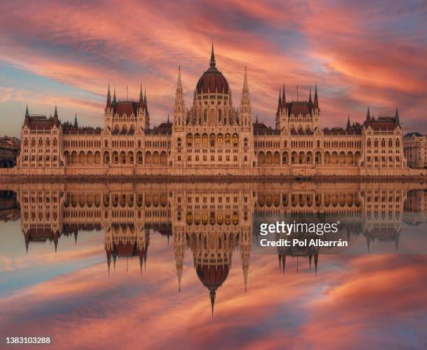 hungarian parliament building along river danube at dawn with colorful clouds sky. - royal palace budapest stock-fotos und bilder