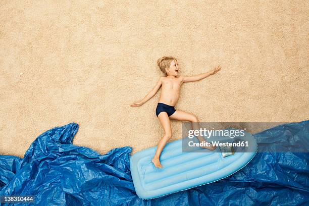 germany, boy on inflatable raft in water at beach - auf dem rücken liegen stock-fotos und bilder