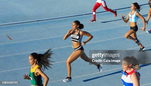 female track and field athletes running in competition on blue track - track and field event stock pictures, royalty-free photos & images