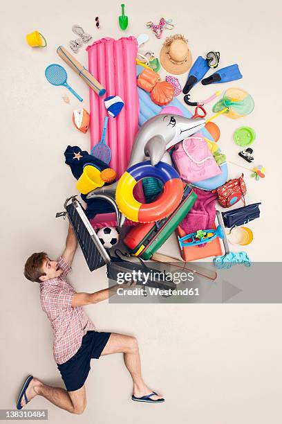 germany, artificial scene with man opening baggage full of beach toys - luftmatratze von oben stock-fotos und bilder