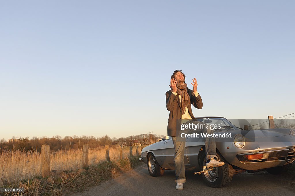 Germany, Hamburg, Man changing tyre of classic cabriolet car