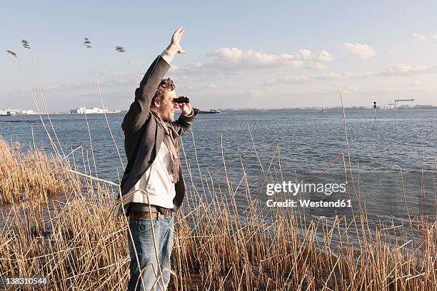 germany, hamburg, man looking through binoculars near elbe riverside - elbe stock-fotos und bilder