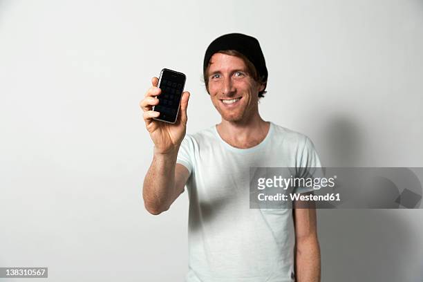 man holding mobile phone, smiling - mostrare foto e immagini stock