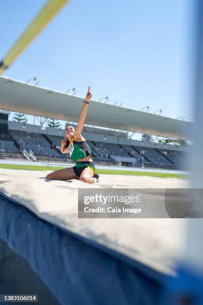 happy female track and field athlete celebrating high jump - sporthesje stockfoto's en -beelden