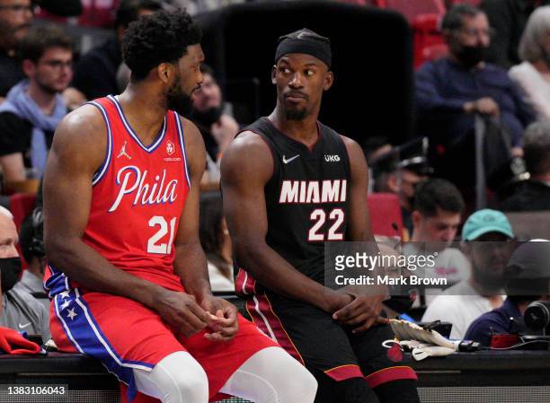 Joel Embiid of the Philadelphia 76ers speaks with Jimmy Butler of the Miami Heat while waiting to enter the game in the first half at FTX Arena on...