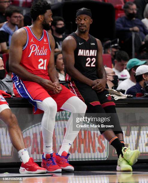 Joel Embiid of the Philadelphia 76ers speaks with Jimmy Butler of the Miami Heat while waiting to enter the game in the first half at FTX Arena on...