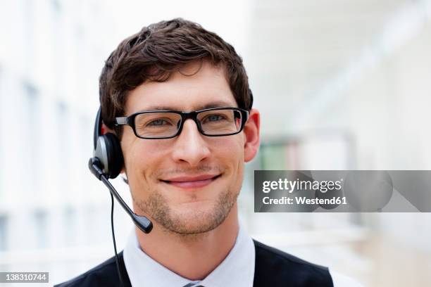 germany, bavaria, diessen am ammersee, close up of businesssman with headset, smiling, portrait - dicke-brillenfassung stock-fotos und bilder
