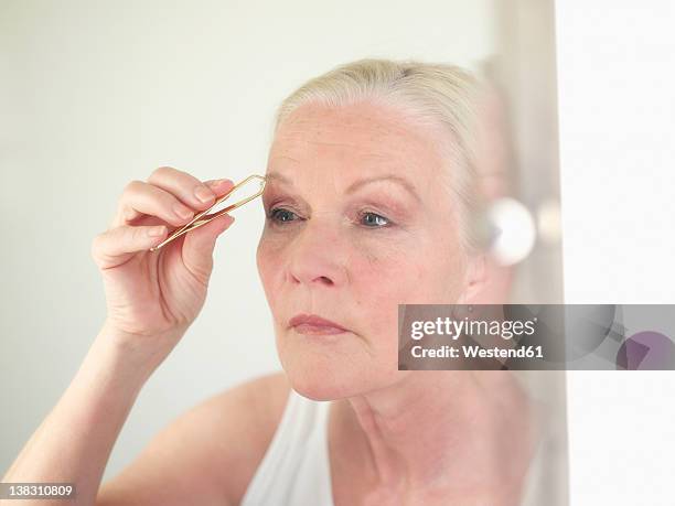 senior woman using tweezers, close up - eyebrow tweezers imagens e fotografias de stock