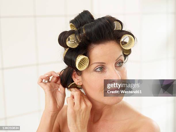 mature woman in towel with hair rollers, smiling - hair curlers stock-fotos und bilder