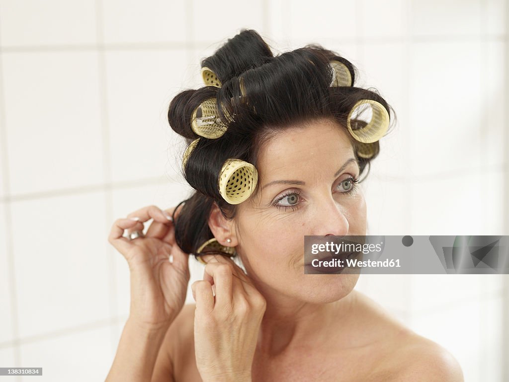 Mature woman in towel with hair rollers, smiling