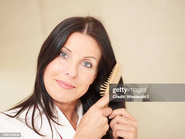 mature woman using hair brush, smiling, portrait - hair brush stock pictures, royalty-free photos & images