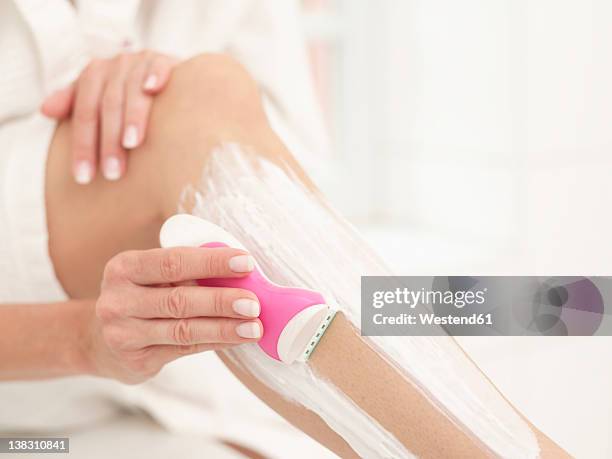 close up of mature woman using razor - shaving cream stockfoto's en -beelden