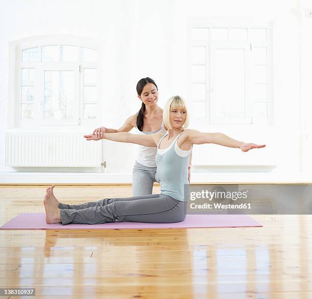 germany, hamburg, yoga instructor corrects woman doing yoga exercise in gym room - pilates abstract stock pictures, royalty-free photos & images