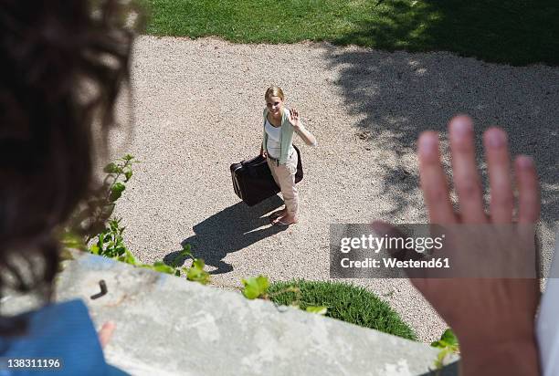 italy, tuscany, view of young woman with luggage from hotel window - waving stock-fotos und bilder