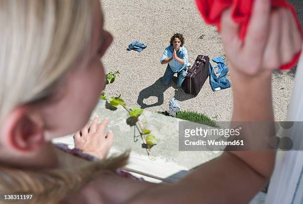 italy, tuscany, view of guilty young man with luggage from hotel window - lancio foto e immagini stock