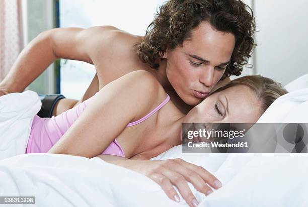 italy, tuscany, young couple romancing on bed in hotel room - man and woman kissing in bed stock pictures, royalty-free photos & images