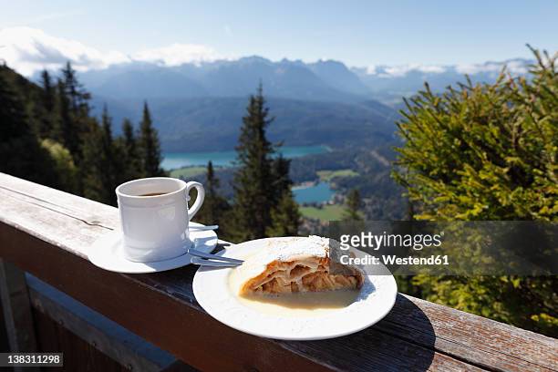 germany, bavaria, upper bavaria, apple strudel and coffee cup on fence with mountains in background - strudel dessert stock-fotos und bilder